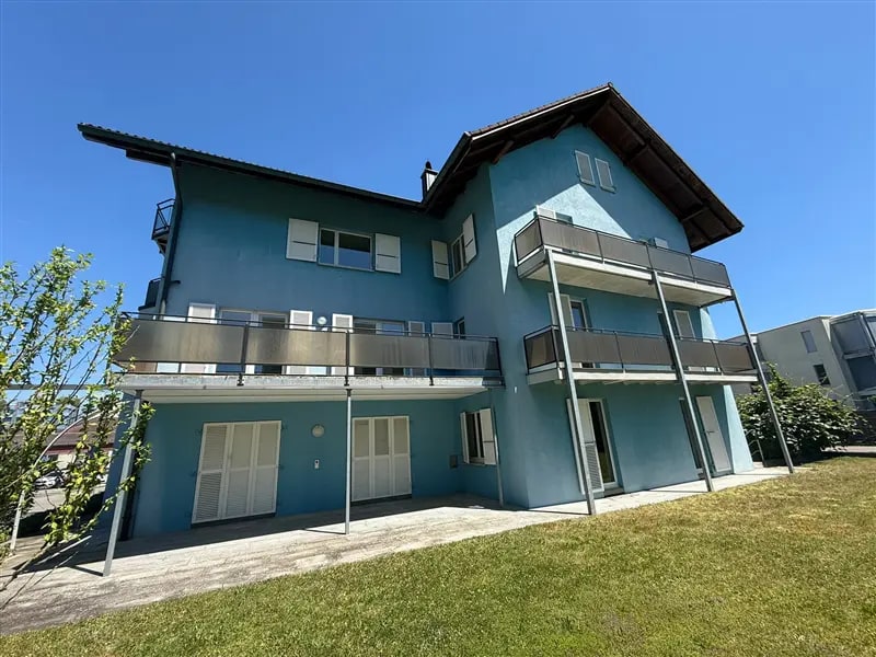 Mehrfamilienhaus mit blauer Fassade und Balkonen unter blauem Himmel