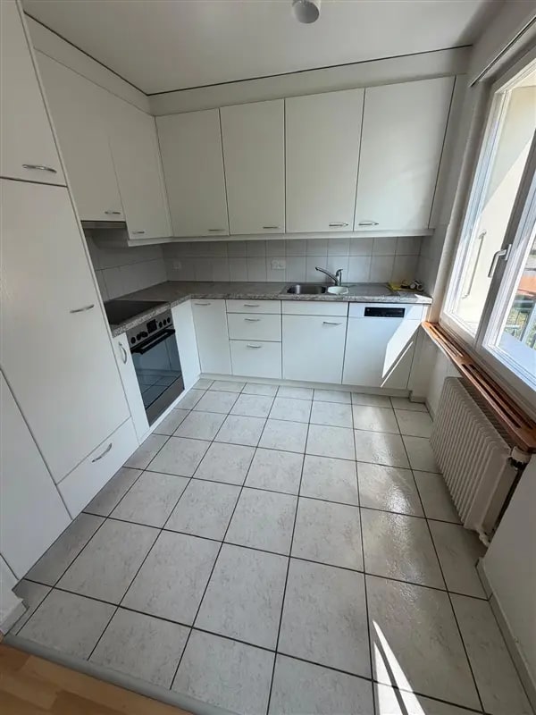 Küche mit weissen Schränken und sauberem Plattenboden