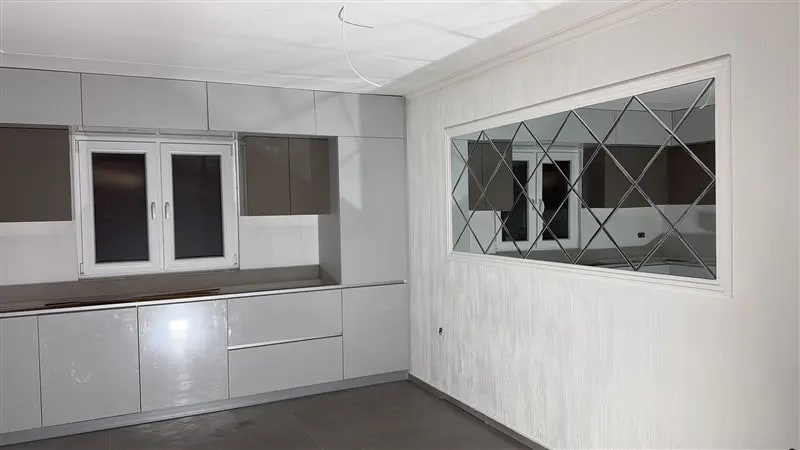 Küche mit weisser, strukturiert verputzter Wand und Spiegelfeld
