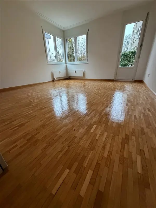 Heller Raum mit glänzend poliertem Parkettboden und Eckfenstern