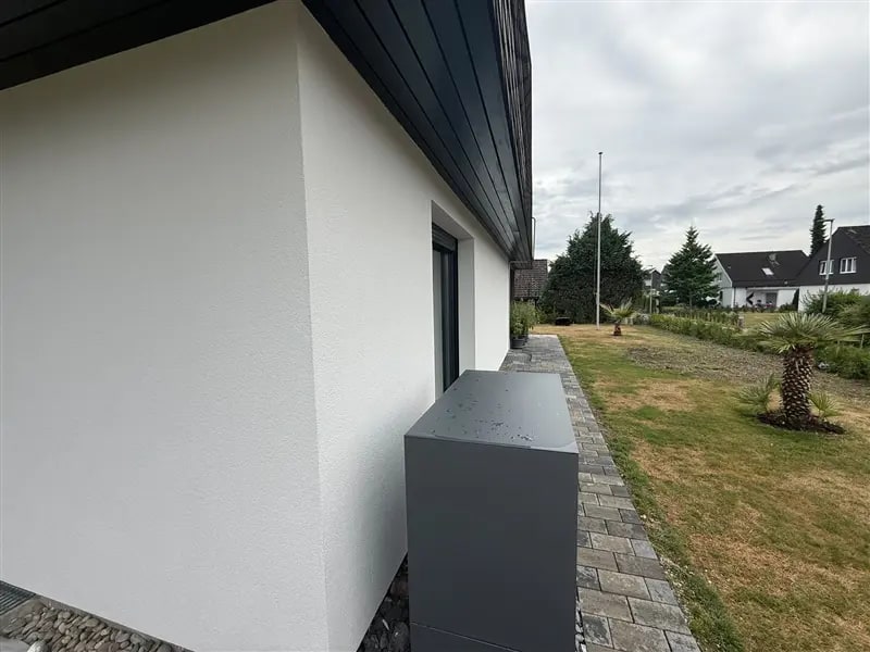 Weisse Hausfassade mit feinem Rauputz, Hausecke und Garten